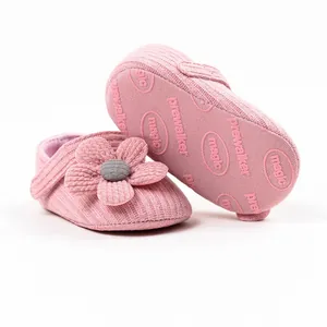 Detail view of pink knitted baby prewalker shoe with non-slip sole and flower