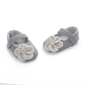 Detalle de bonitos zapatos grises para bebé niña con adorno de flor y botón