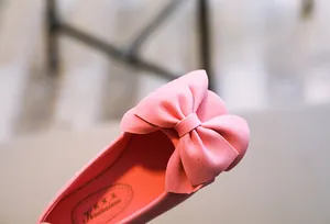 Nahaufnahme eines rosa Mädchenschuhs aus Wildleder mit einer großen, dekorativen Schleife