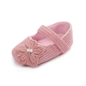 Dettaglio di scarpe principessa in maglia rosa per neonata con fiore 3D e perle