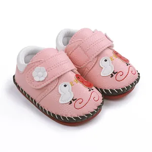 Detalle de zapatos rosa para bebé con bordado de pájaro y correa de flor