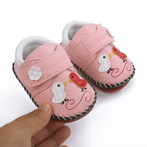 Primer plano de zapatos de cuero rosa hechos a mano para bebés con dibujos de aves
