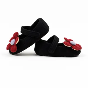 Close-up view of black knitted baby girl princess walker shoes with large red flower accents