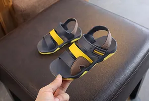 Detail view of stylish boy's summer beach sandals in grey, yellow, and brown colors