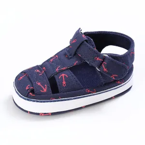 Detailed view of a baby walking sandal with a red nautical anchor pattern in navy blue.