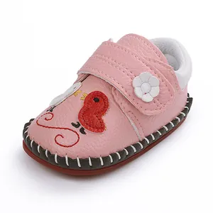 Detalle de zapato rosa para bebé con bordado de pollito y tira de flor blanca