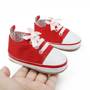 Detailed view of red and white canvas baby walking shoes with cute pink ribbon bow decoration.