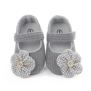 Detalle de zapatos de bebé grises con flor de cuadros y adorno de botón.
