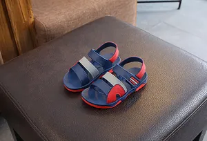Close-up of a pair of boys' blue and red color-block beach sandals on leather.