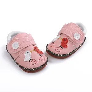 Detalle de zapatos para bebés de color rosa con bordado de pájaros y suela de goma