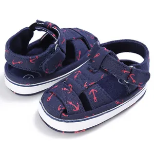 Detail of baby walking sandals featuring a red anchor pattern on navy blue fabric.