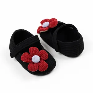 Detail view of black knit baby princess shoes with a vibrant red flower accent