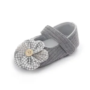 Detalle de zapato de punto gris para bebé niña con flor decorativa de tela y botón de madera