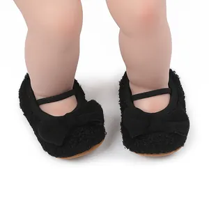 Primer plano de zapatos de peluche negro para bebé con un lazo decorativo y correa elástica