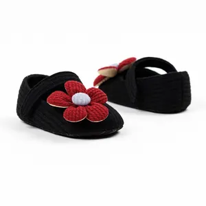 Detailed view of black knit baby girl princess walking shoes with red fabric flower