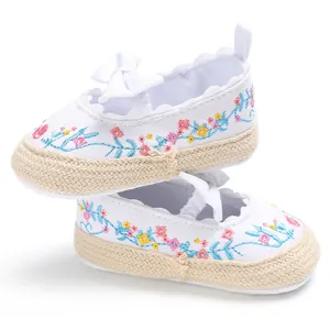 Detail van witte babyschoenen met kleurrijke bloemborduursels en een zachte strik