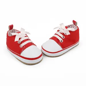 Close-up detail of red and white infant walking shoes with elegant pink ribbon bow