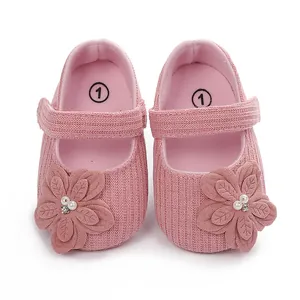 Dettaglio di scarpine rosa per neonati con fiori decorativi in maglia e perle eleganti