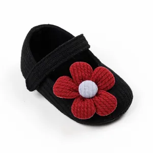Detailed macro view of black knitted baby princess shoes featuring a large red decorative flower
