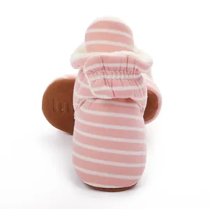Détail de bottes d'hiver pour bébé à rayures roses avec doublure polaire et semelle marron