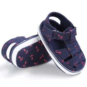 Close-up of navy baby walking sandals with red anchor pattern and white soft sole