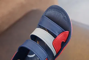 Macro view of boys' beach sandals featuring blue, white and red color-block straps