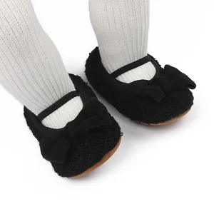 Detalle de zapatos de bebé en felpa negra con un lazo decorativo y una correa elástica