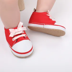 Close-up of red baby walking shoes with pink ribbon laces for 0-1 year old infants.