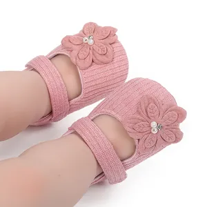 Dettaglio delle scarpe da passeggio per neonata in maglia rosa con fiori decorativi