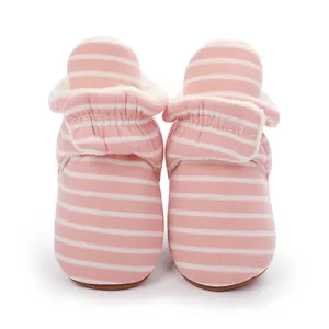Gros plan de bottines d'hiver pour bébé à rayures roses avec doublure en polaire et velcro.
