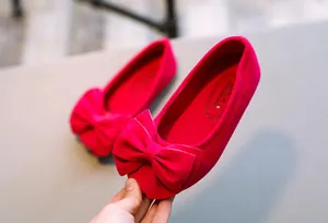 Nahaufnahme von pinkfarbenen Samt-Ballerinas für Mädchen mit großer dekorativer Schleife