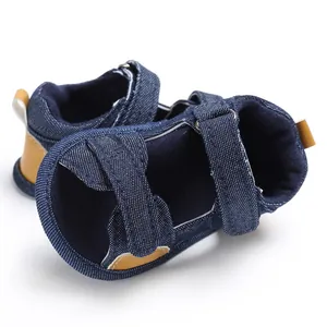 Macro detail of blue denim baby toddler sandals featuring easy velcro straps and brown leather.