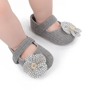 Detailed view of grey knit baby walking shoes with a plaid flower ornament.