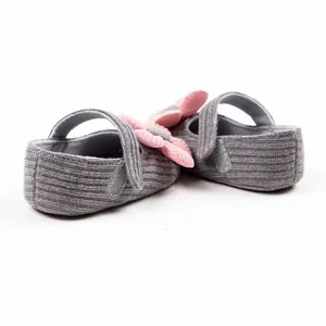 Detail view of gray knitted baby girl princess pre-walker shoes with pink yarn flower