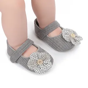 Close-up of grey baby princess shoes with large plaid flower and button detail