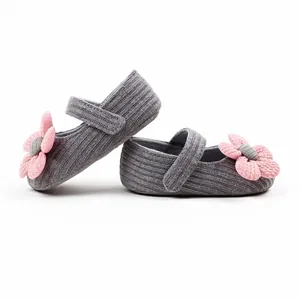Close-up side view of soft grey knit baby Mary Jane shoes featuring pink flower accents