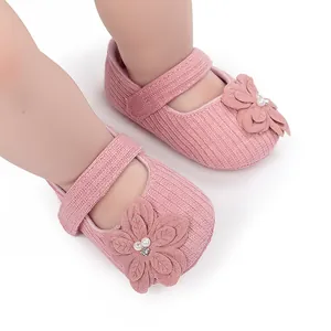 Dettaglio di scarpe primi passi rosa per neonata con fiori, perle e strass
