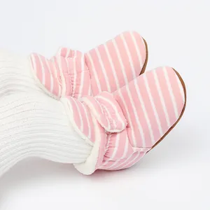 Gros plan sur des bottines d'hiver rayées roses pour bébé avec doublure polaire chaude