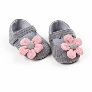 Close-up detail of grey knitted baby shoes with soft pink flower applique decoration