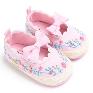 Detail van roze geborduurde babyschoentjes voor meisjes met strik en bloemmotief
