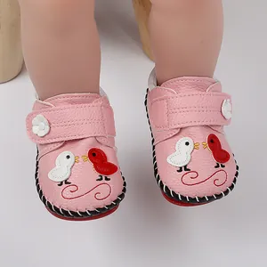 Primer plano detallado de zapatos rosas para bebé con bordado de pájaros y tira de flores