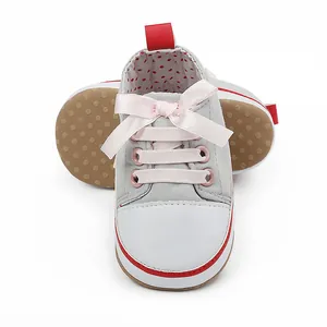 Detailed view of grey canvas baby girl shoes with pink ribbon bow and red accents