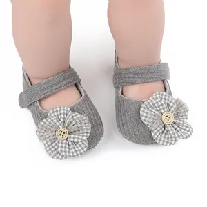 Detalle de zapatos de gateo grises para bebé con una flor decorativa de tela vichy