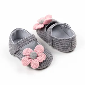 Close-up of baby girl grey knit walking shoes with a decorative pink flower detail