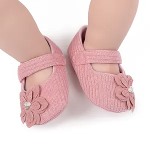 Vista dettagliata di scarpine neonato in maglia rosa con fiore 3D e decoro perla