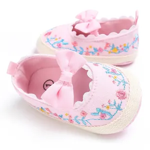 Detailopname van roze baby prinsessenschoenen met bloemenborduurwerk en strik