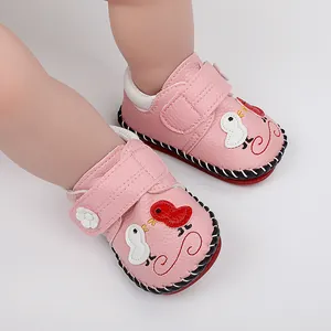 Primer plano de zapatos de bebé rosa con bordado de pájaro y suela de goma suave.