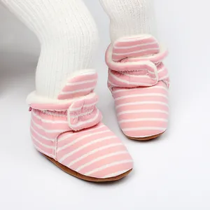 Détail de bottines pour bébé à rayures roses avec doublure en polaire chaude et velcro.