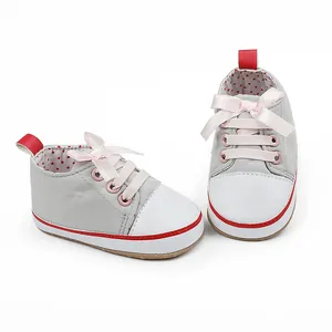 Close-up of baby pre-walker shoes with pink ribbon bow and red polka dot lining.