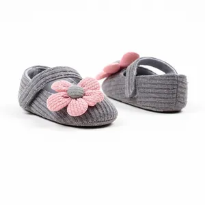Close-up detail of grey knitted baby girl walking shoes featuring a decorative pink flower